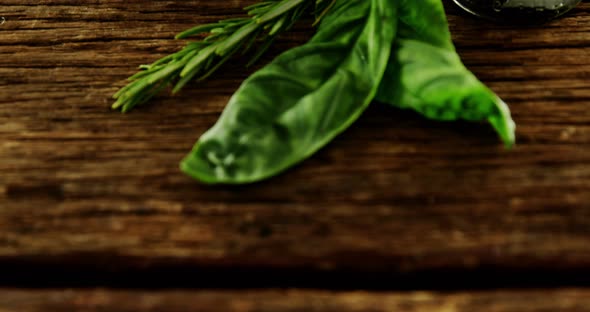 Herbs and bowl of red olives on wooden table alt