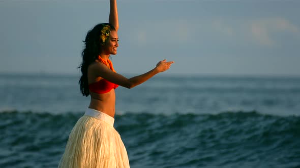 Hula dancer performs by ocean waves, slow motion alt