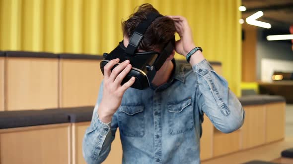 Attractive Young Man Puts on VRheadset and Starts Playing VR Video Games alt