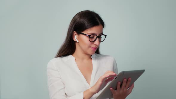 The Girl Works in the Office with a Tablet in Headphones