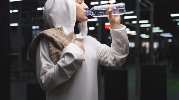 Muslim Woman in a Sports Hijab in the Gym a Woman Drinks Water During a Workout