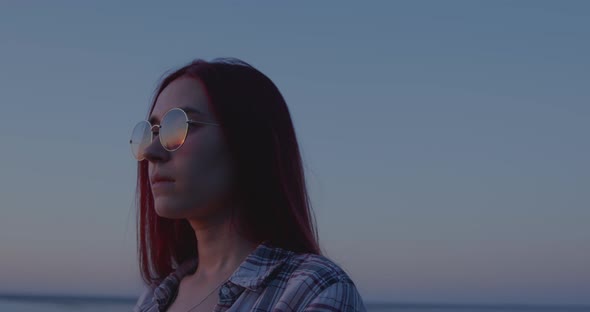 A girl with a pensive look at sunset looks into the distance alt