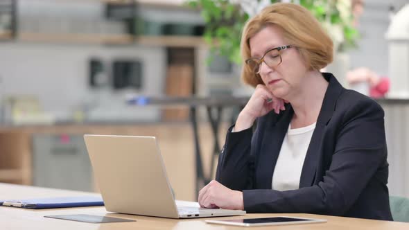 Old Businesswoman with Laptop Having Nap in Office alt