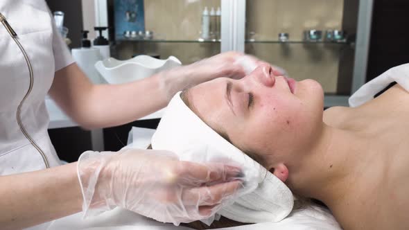 A Cosmetologist Cleans the Face of a Client with a Napkin in a Beauty Salon