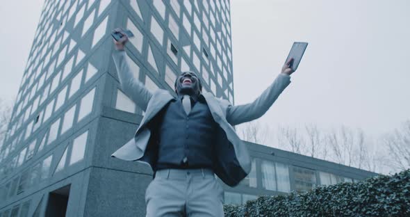 Happy african man feeling euphoric and celebrating outside a skyscraper alt