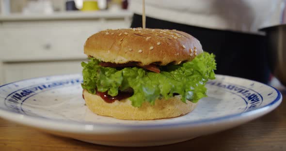 Chef Puts French Fries on a Plate with a Large Burger. Slow Motion. Close Up alt