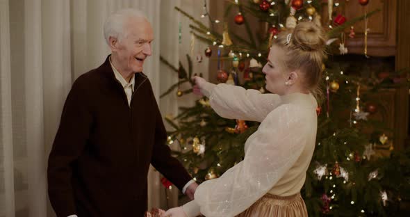 Woman Giving Christmas Present To Grandfather At Home alt