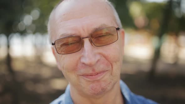 Close Up Shot of Elderly Man in Glasses Looking at Camera with Neutral Face Expression and Then