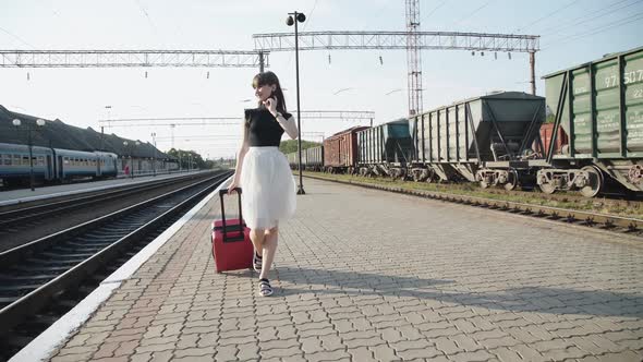 Happy Lady Goes with Suitcase and Poses with Dress on Railway Platform alt