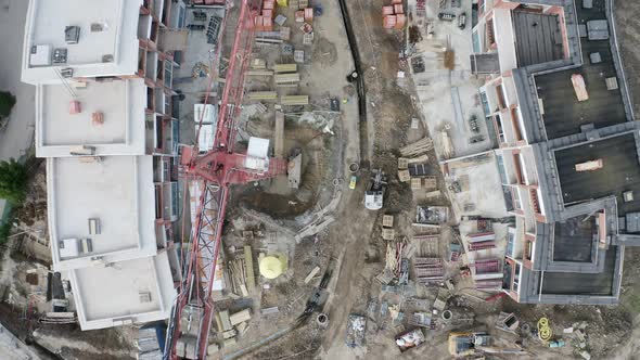 Overhead view of red steel cranes at a residential construction site. alt