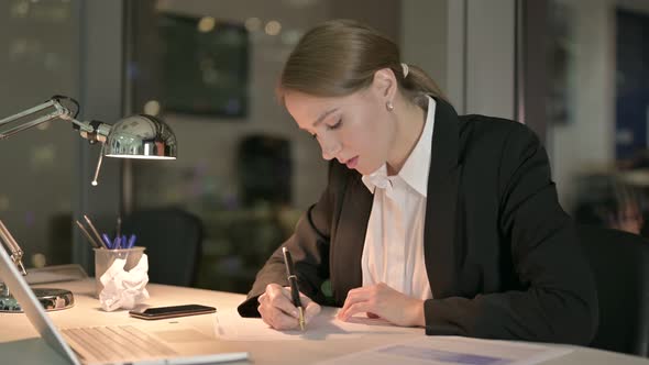 Businesswoman Thinking and Working on Document at Night  alt