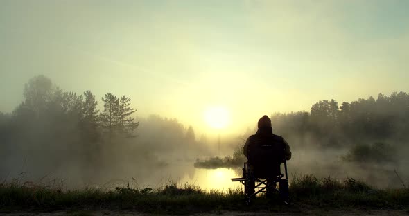 Unrecognizable Man Fishing in Lake at Dawn