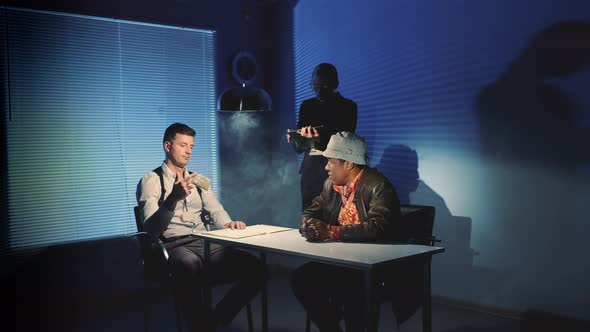 Interrogation Room in Smoke: Detective Showing Evidence of Drug Trafficking To Suspected Black Man alt