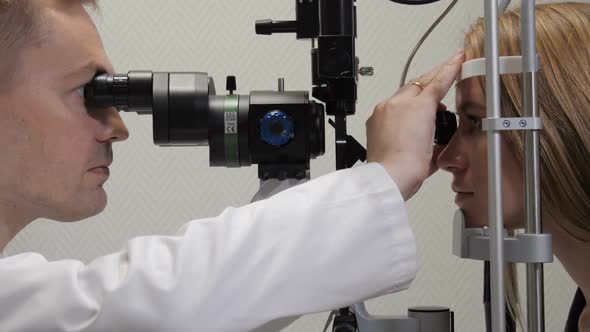 Doctor Looks at Patient's Eyes with a Microscope and Magnifier alt