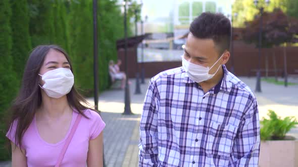 Two Young Asian Students in a Medical Mask on His Face Walking Down the Street and Talking Close Up alt