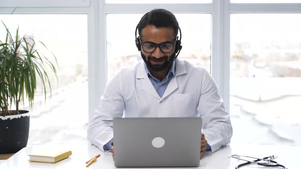 Indian Male Conference Speaker in a Medical Gown Glasses and a Headset alt
