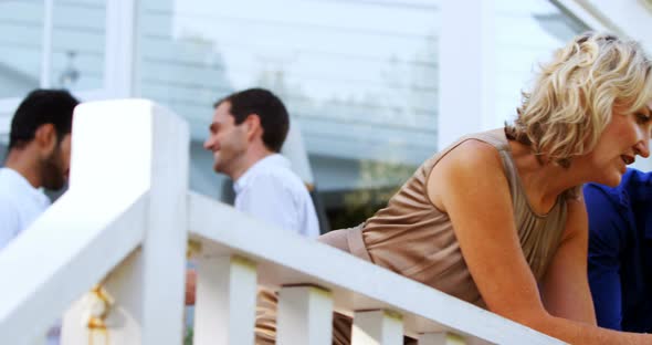 Friends interacting while having champange in balcony alt