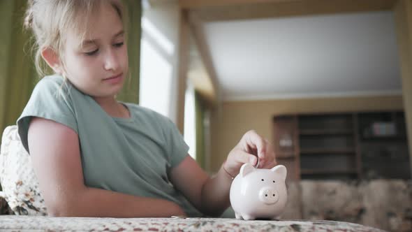 Girl Putting Coin in Piggy Bank Saving Money Concept alt