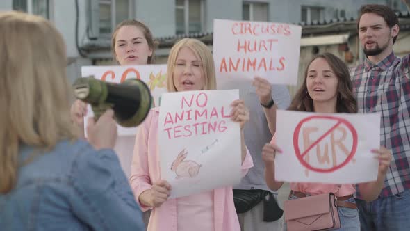 Crowd of People Defending Animal Rights in Urban City with Blurred Woman Shouting Through Megaphone alt