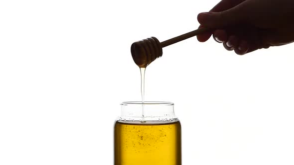 Glass Jar of Honey with Wooden Spoon, Pick It Up, Isolated on White, Slow Motion alt