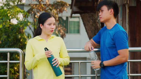 Happy young sporty couple taking a break from work out and drinking water. alt