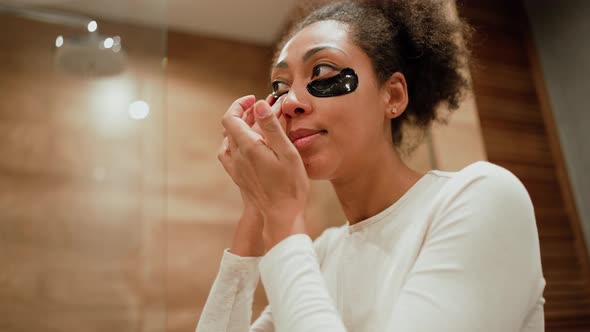 Handsome African pregnant woman apply patches under the eyes alt