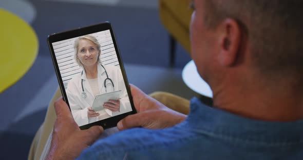 Senior man having a video chat on his digital tablet at home alt
