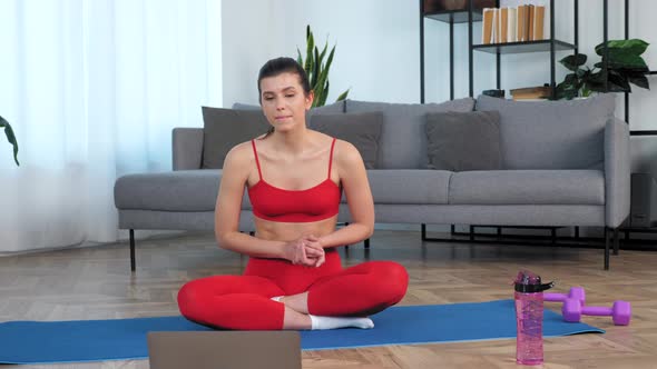 Camera Zoom in Woman Sits on Yoga Mat Listen Talk Fitness Trainer Study Online alt