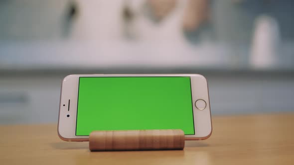 Mobile Phone with Green Screen Is Standing on the Table alt