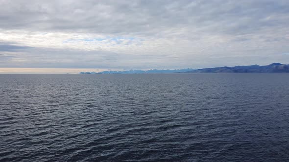 View from a ferry, mountain chains of the Lofoten island far away. Calm northern sea in Norway. alt