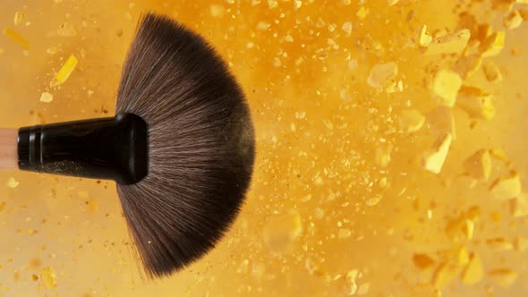 Super Slow Motion Shot of Makeup Brush and Golden Powder Explosion at 1000 Fps alt