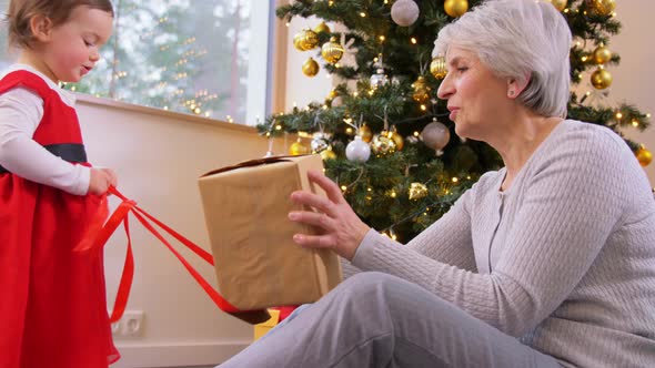 Grandmother and Baby Girl Opening Christmas Gift alt