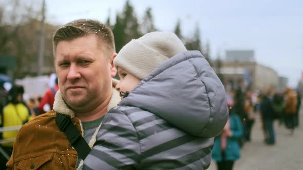 Single Dad with Kid in Arms Walking at Protest Demonstration