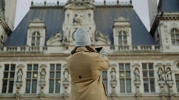 Young woman in a gray hat makes a picture on the phone in Paris in autumn alt
