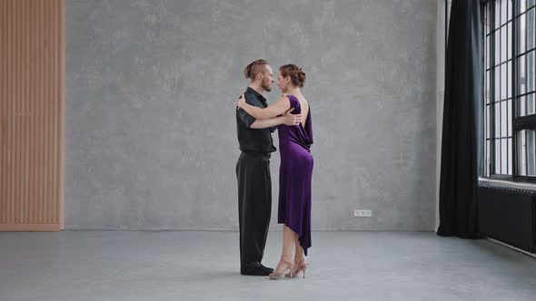 Full Growth Shot of a Pair Dancing Tango in Grey Studio with Large Windows