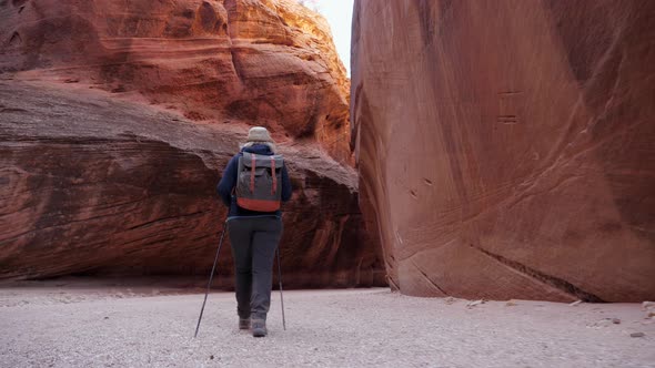 Tourist Trekking On Sandy Desert In Slot Canyon With Orange Rock Formation alt