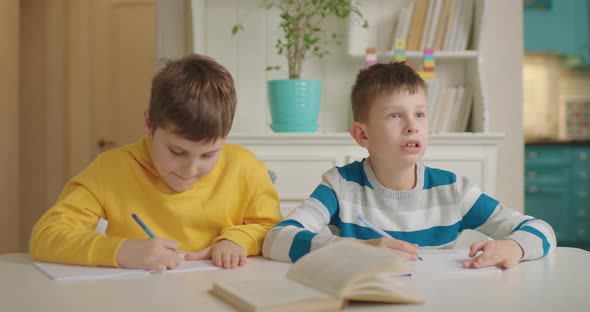 Two Boys with Autism Have Writing Lesson Sitting at the Table alt