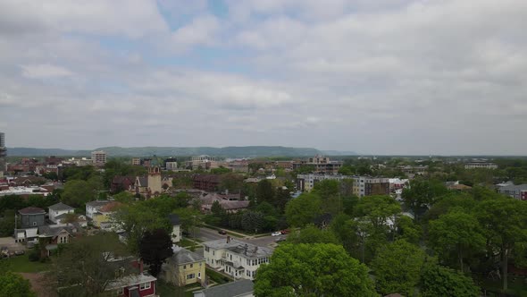 Aerial view of established city neighborhood with church and residential homes with trees.