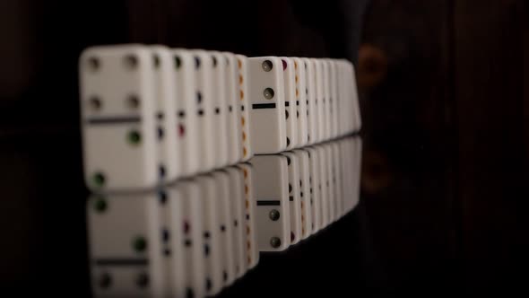 A Hand Pushing Dominoes on a Black Mirror Surface alt