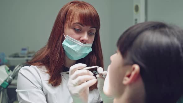 Beautiful stomatologist examines the patient with special tool in dental office. alt