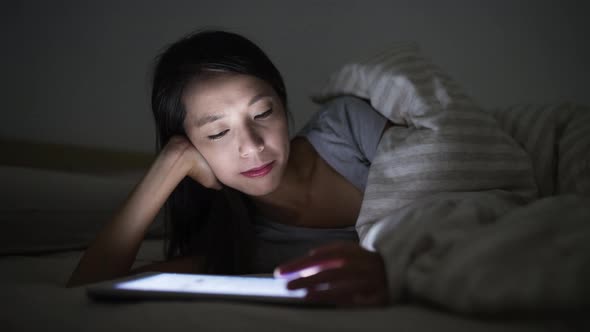 Time lapse of woman using digital tablet on bed at night  alt