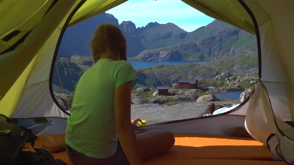 A Girl Sits in a Tent and Looks at the Beautiful Nature of Norway alt