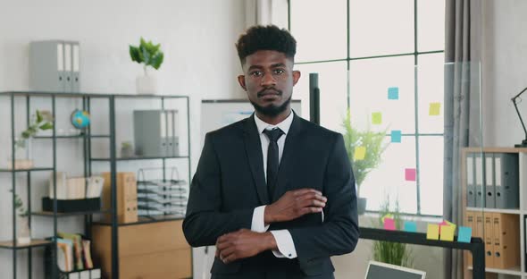 Businessman in Suit Posing on Camera with Crossed Arms in Modern Office Room at Daytime alt