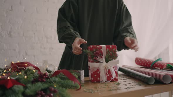 Young Beautiful Woman Gift Wrapper Wraps Up a Christmas Gift and Decorates with Decorative alt