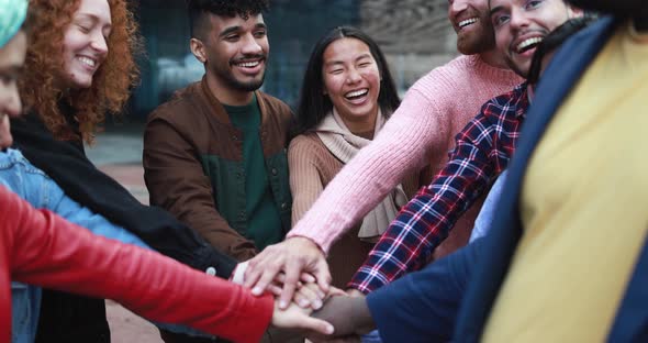 Group of happy young people stacking hands outdoor alt