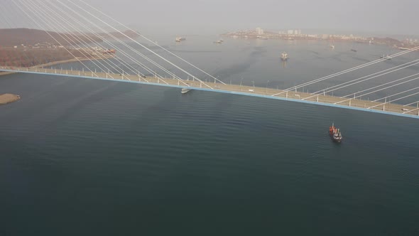 Drone View of a Modern Corvetteclass Ship Going Out to Sea Under the Bridge alt