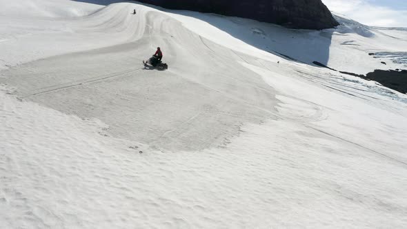 Rider Snowmobiling At Langjokull Mountain On A Sunny Winter Day In Iceland. - aerial alt