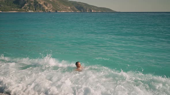 Relaxed Handsome Athletic Man in Blue Swim Trunks Enjoying By Lying on Turquoise Water of alt