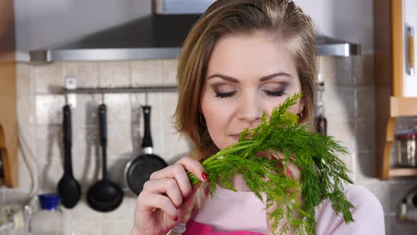 Girl Smelling Dill Herb in Kitchen