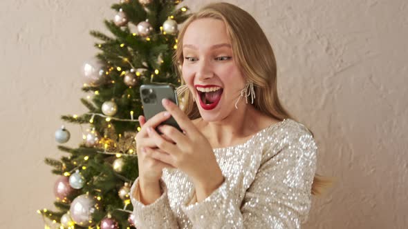 Amazed lucky christmas woman using mobile phone looks and sees the message with a good news. alt